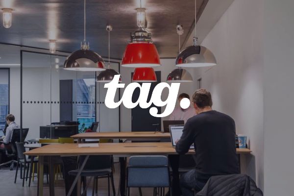 people work at corporate desks with the tag logo as an overlay